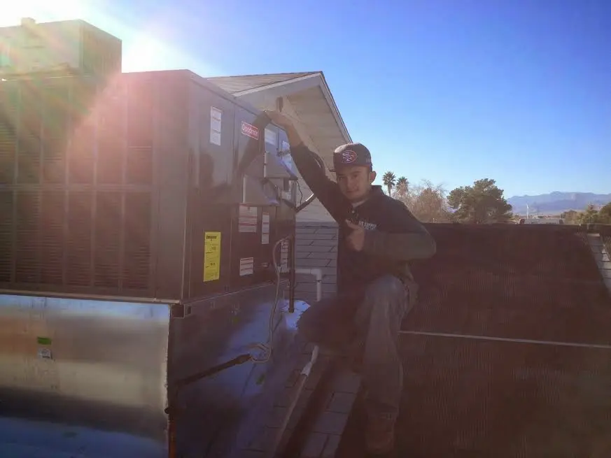 HVAC technician performing Heat Pump Repair on a rooftop unit in La Grande